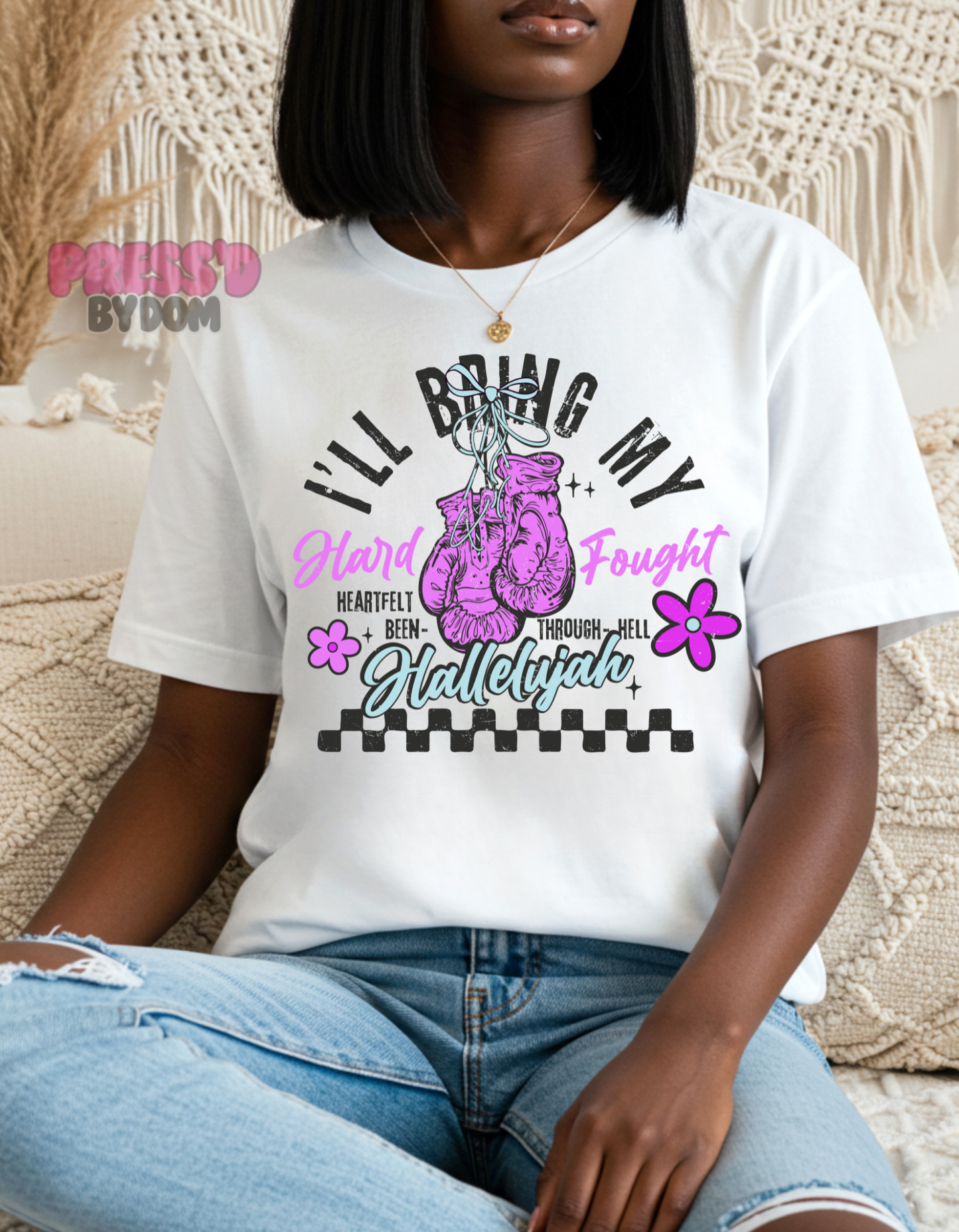 Woman wearing white graphic tee with pink boxing gloves that reads “I’ll Bring My Hard-Fought Hallelujah” – faith-based shirt by Press’d by Dom
