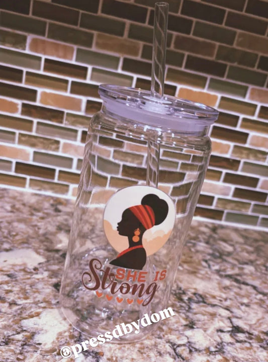 She Is Strong glass cup with silhouette of a Black woman wearing a red headwrap, comes with straw and lid – faith-based drinkware by Press’d by Dom.